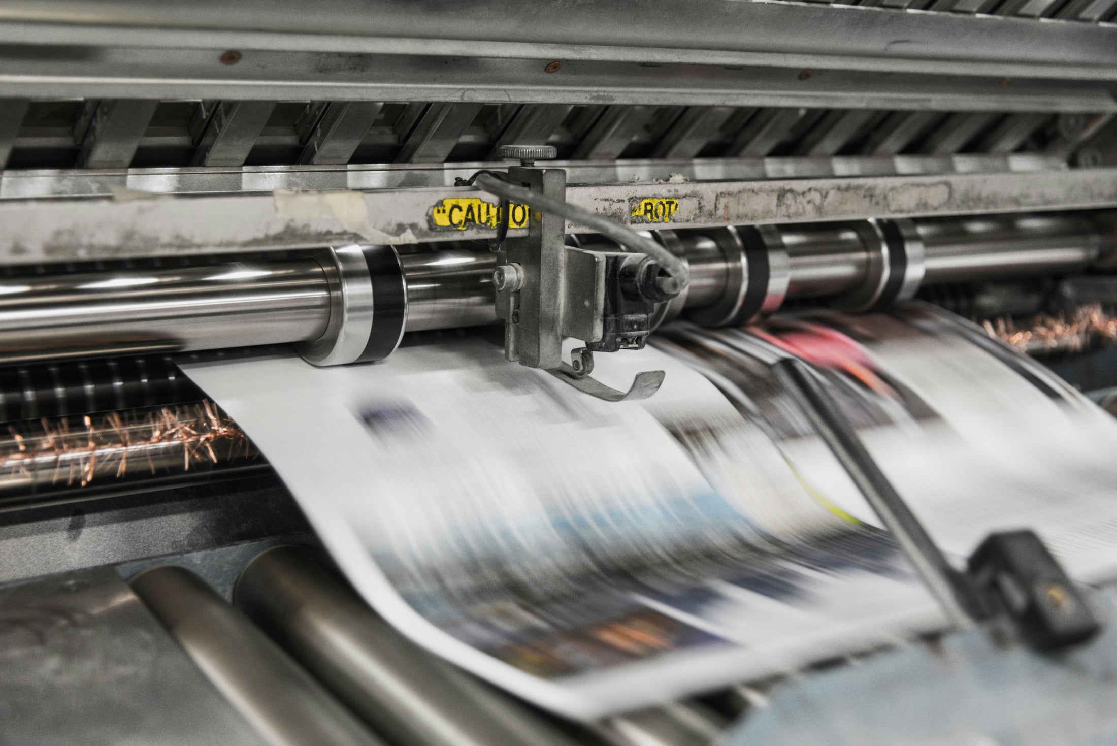 Industrial printing press running printed sheets through rollers, sublimation vs DTF printing guide