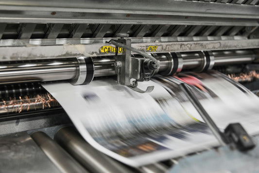 Industrial printing press running printed sheets through rollers, sublimation vs DTF printing guide