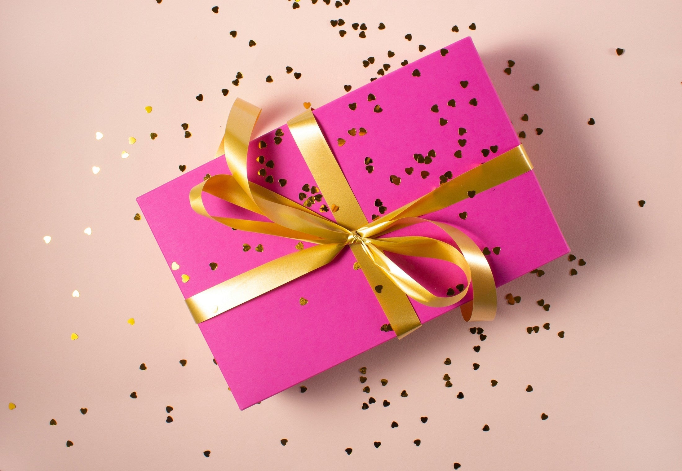 Pink gift box with gold ribbon and confetti, bulk employee Christmas gifts and corporate Q4 gifting programs from Photo USA