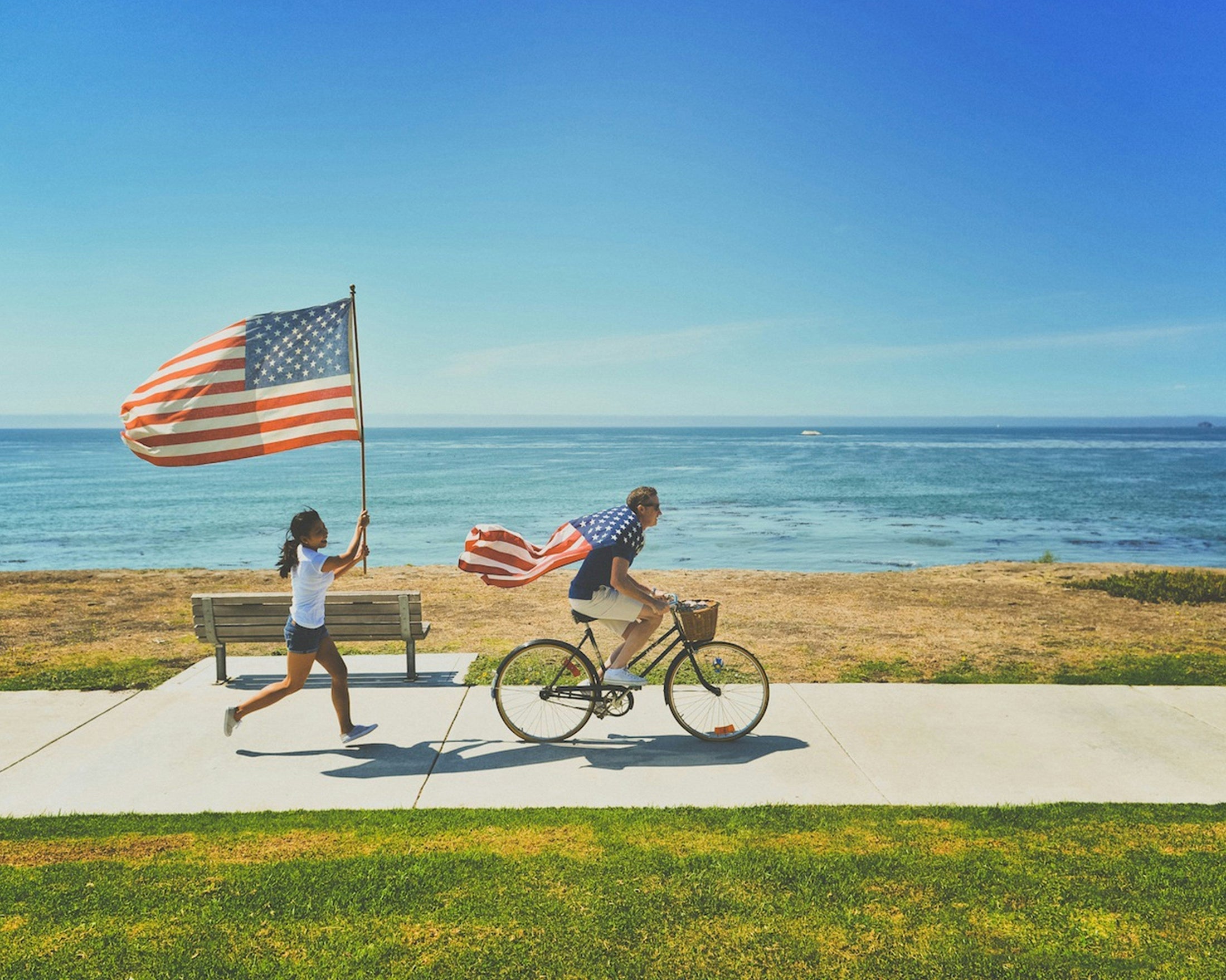 People celebrating July 4th 2026 outdoors with American flags — custom sublimation tumblers for bulk office gifts and employee appreciation from PhotoUSA