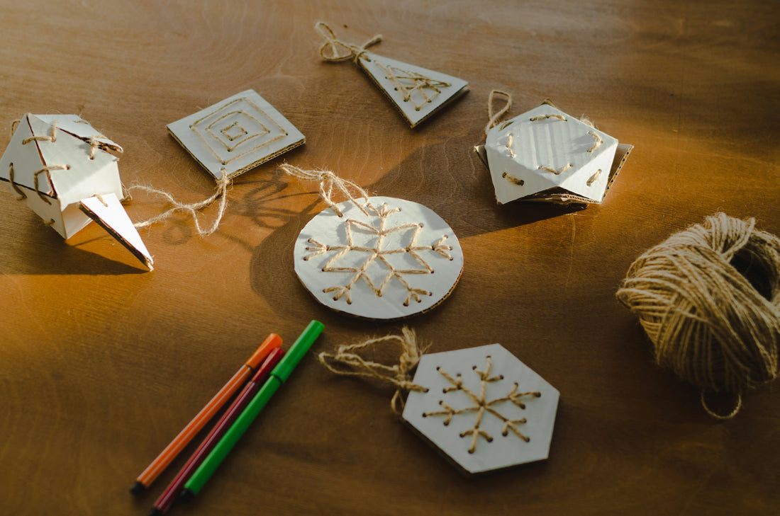 An assortment of white ceramic ornaments in circle, snowflake, tree and hexagon shapes with hanging string on a wooden table, illustrating wholesale sublimation ornament blanks from Photo USA