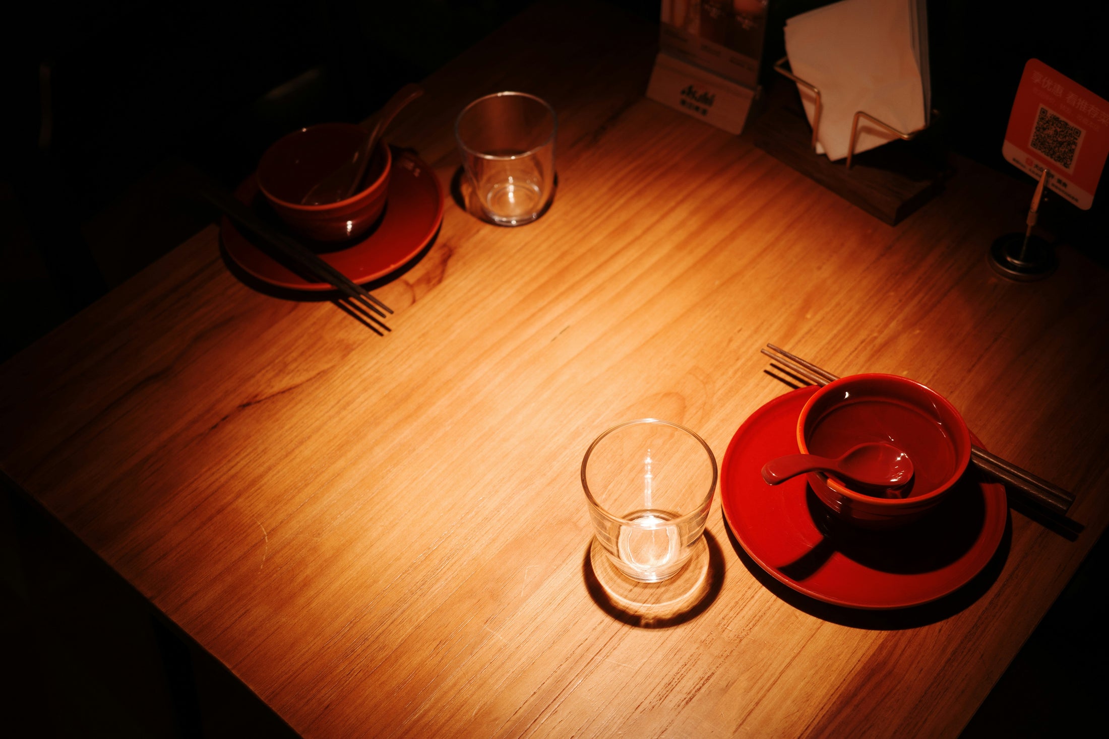 Warmly lit wooden table set with red bowls and glasses, ready for a holiday craft night hosted with Photo USA wholesale sublimation blanks